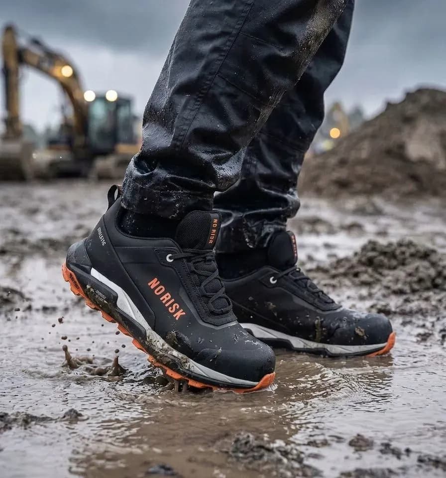 Atmospheric image of No Risk Athletic Low STX Orange on a wet construction site